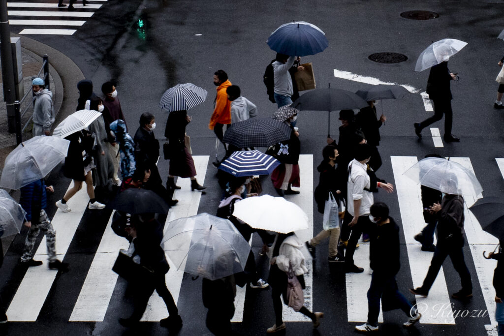 群衆に紛れる、渦巻く様な柄の傘。歩道橋の上から撮影。