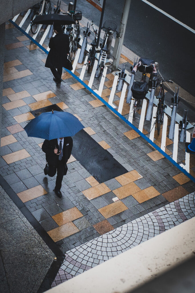 傘を刺して歩く男性のストリート写真