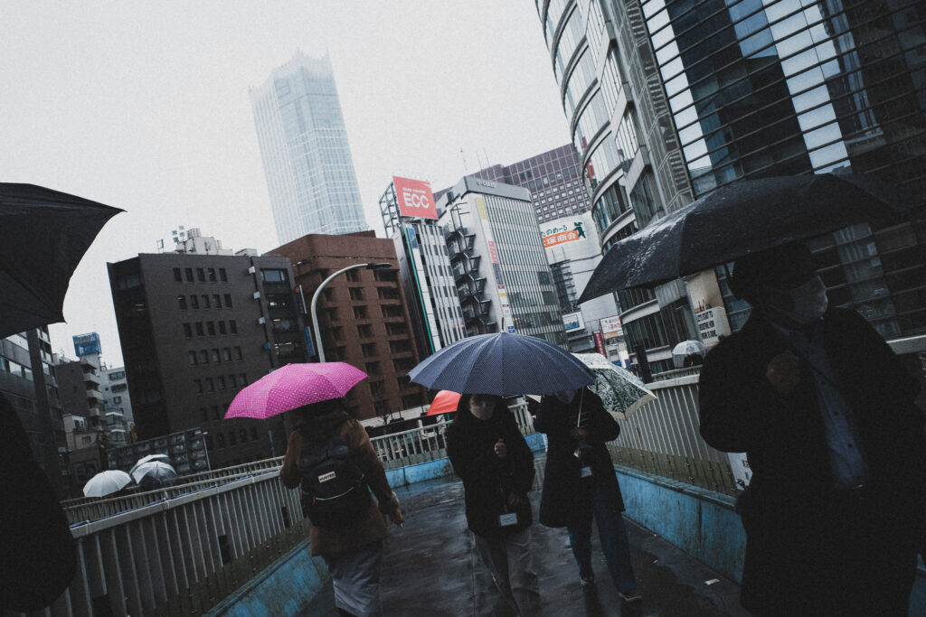 歩道橋の上を歩く傘の人々のストリート写真