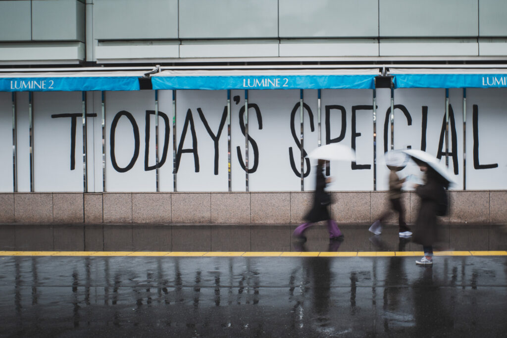 新宿ルミネ２前を歩く、傘の人々の写真