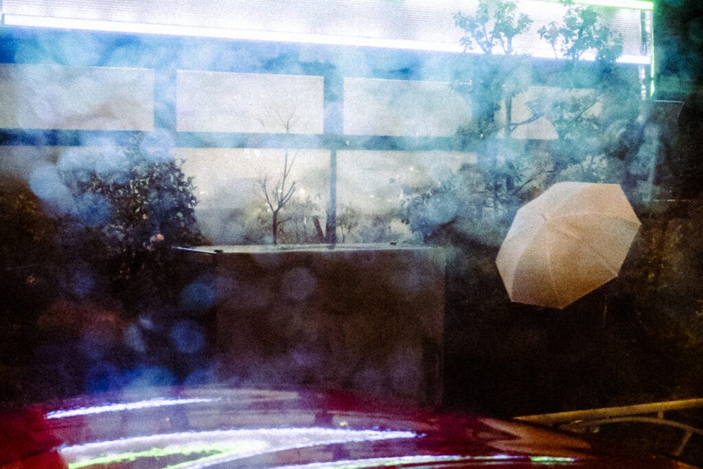 窓ガラスの水滴による光の拡散越しに撮影した、美しい白い傘のスナップ写真